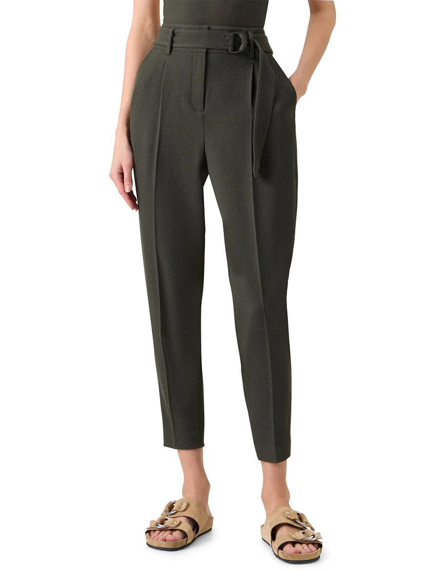 Wearing Akris Punto Fred Belted High Rise Ankle Pants in Olive with a tapered fit and belted waist, hands in pockets, styled with beige sandals.
