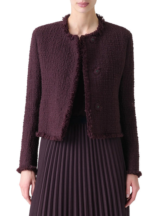 A woman wears the Akris Punto Tweed Round Neck Jacket with Fringe in Blackberry over a matching pleated skirt.