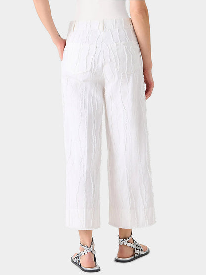 Person wearing Akris Punto Chiara Fringed Wave Jacquard Wide Leg Pants in Cream and black-and-white sandals, standing against a plain light gray background.