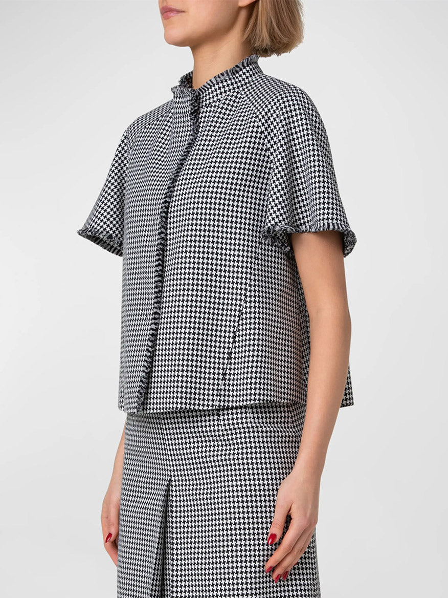 A person in an Akris Punto Fringe Houndstooth Short Sleeve Jacket in Black/Cream and matching skirt with eyelash fringed edges. The individual's face is not visible.