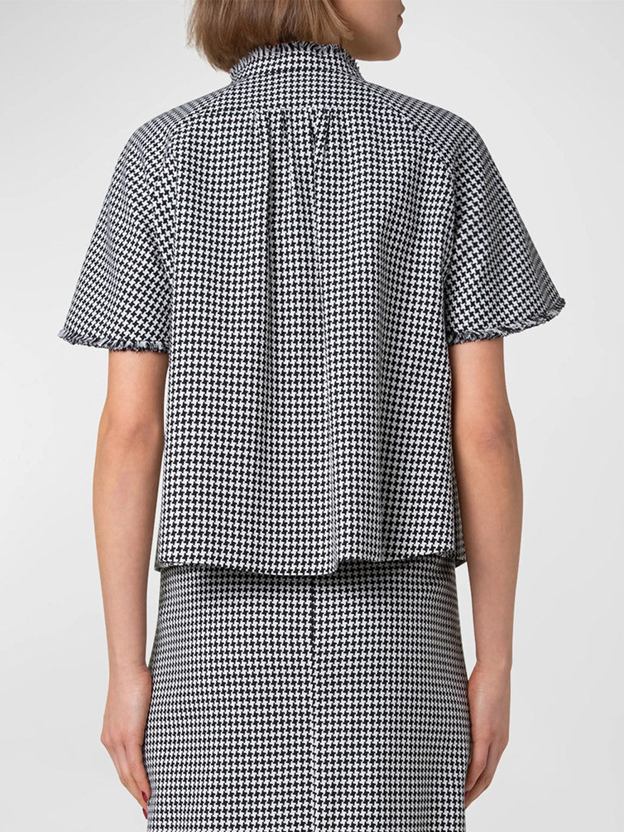 A person wearing an Akris Punto Fringe Houndstooth Short Sleeve Jacket in Black/Cream and skirt, viewed from the back, featuring eyelash fringed edges.