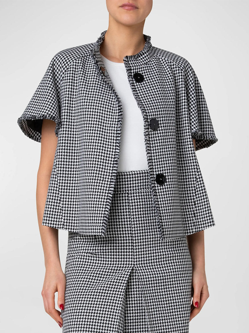 Woman wearing an Akris Punto Fringe Houndstooth Short Sleeve Jacket in Black/Cream over a white top, paired with a matching skirt.