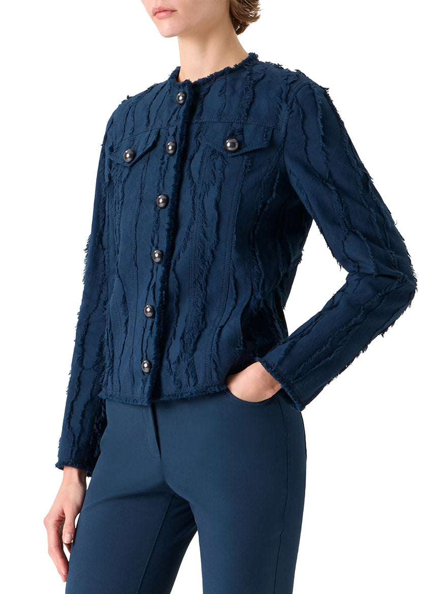 Wearing the Akris Punto Fringed Wave Jacquard Jacket in dark blue, a person poses with one hand in their pocket, paired with matching navy blue pants.
