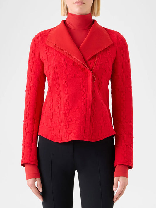 A woman models the Akris Punto Glencheck 3D Jersey Biker Jacket in Vermillion over a red turtleneck and black pants, standing against a plain light background.