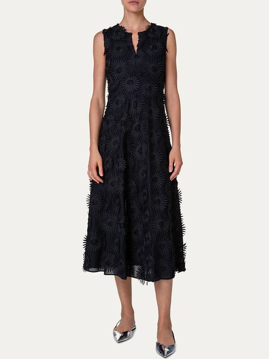 A person in a Akris Punto Hello Sunshine Embroidered Dress in Black, featuring embroidery and a flower pattern, standing against a white background.