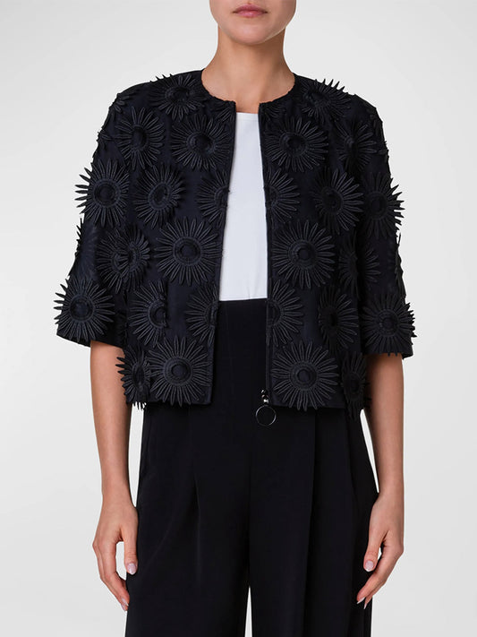 Woman wearing a black floral appliqué Akris Punto Hello Sunshine Embroidered Elbow-Sleeve Jacket over a white top and black trousers.