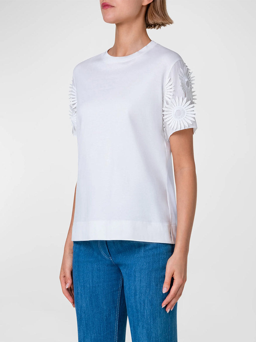 Woman wearing an Akris Punto Hello Sunshine Embroidered Sleeve Tee in Cream and blue jeans.