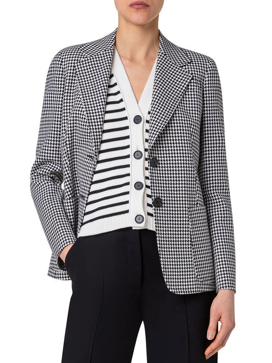 Person wearing a black and white Akris Punto Houndstooth 2-Button Jacket in Black/Cream with notch lapels over a white and black striped cardigan, paired with black trousers. This ensemble seamlessly combines elegance and modern style, reminiscent of Akris Punto's timeless designs.