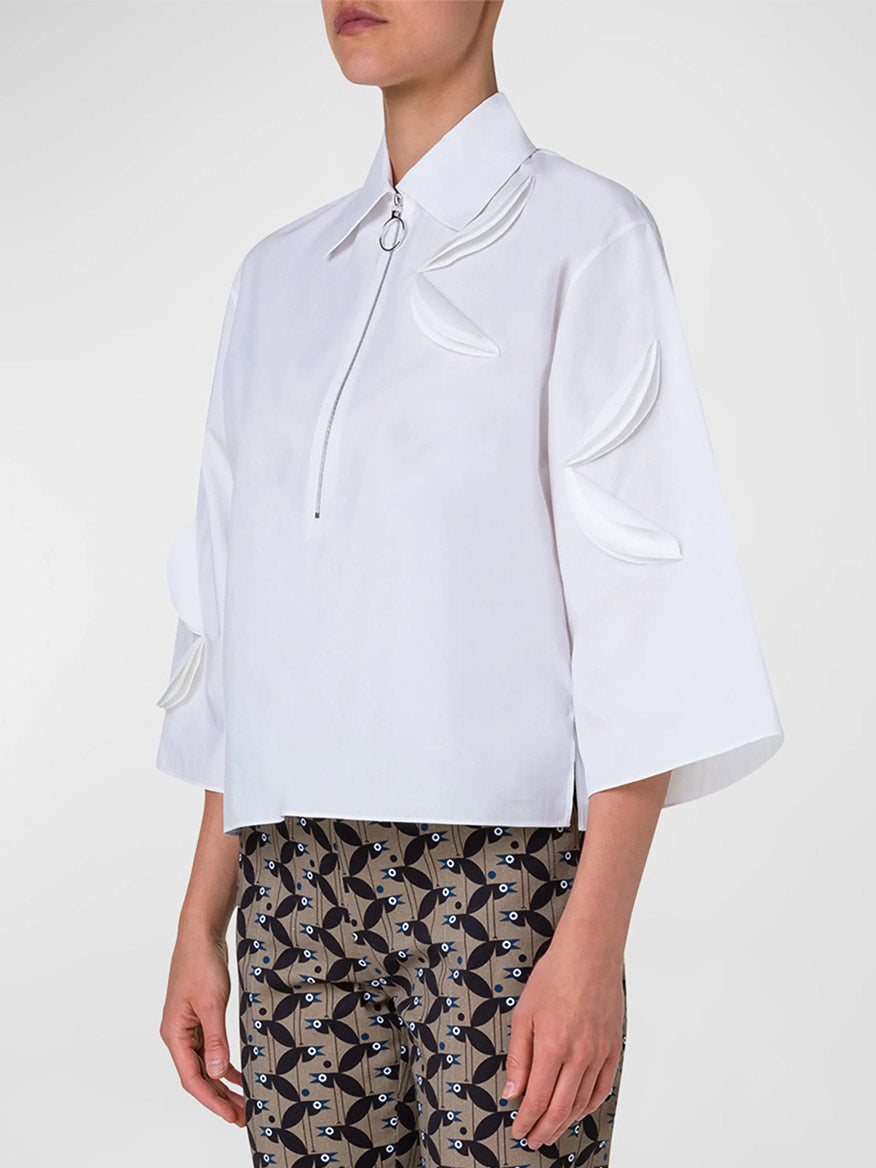 The model is wearing an Akris Punto Kimono Sleeve Blouse With Bird Applique in Cream and patterned pants.