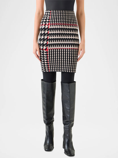 A person wearing a black top, black tights, knee-high black boots, and the Akris Punto Fitted Wool-Blend Plaid Jacquard Skirt in Black/Cream/Vermillion featuring a houndstooth pattern with red accents and a high-rise waistband.