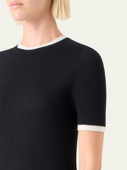 Person wearing an Akris Punto Layered Short-Sleeve Knit Sweater in Black/Cream, featuring contrasting cream trim on the collar and sleeve ends, viewed from the shoulder up.