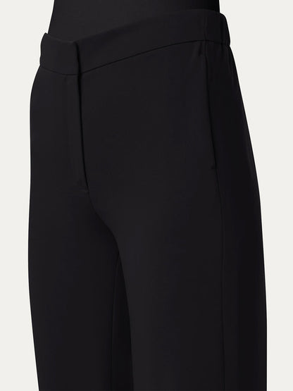 Close-up of a person wearing Akris Punto Marla Wide Straight Lasercut Trousers in black, showcasing the precise waistband with an elastic waistline and side seam detail.