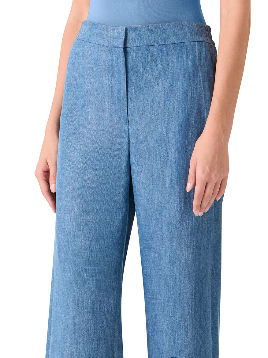 Person wearing Akris Punto Marlon Washed Denim Circle Lace Pants in Medium Blue, featuring a signature dot motif and wide-leg design, paired with a blue top. Shown from mid-torso to knees, with one hand resting by their side.