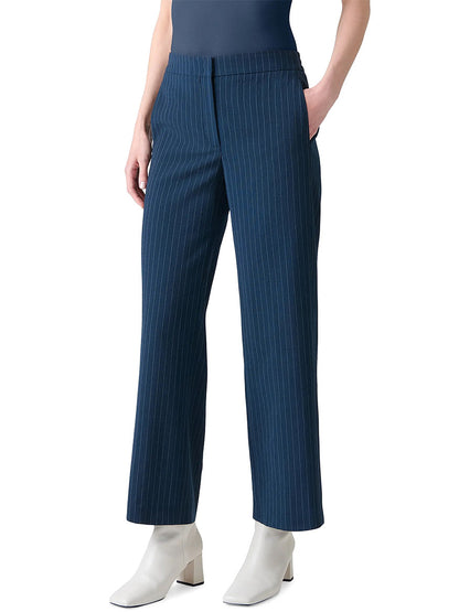 A person wearing Akris Punto Marlon Pinstripe Wide Leg Pant in Navy/Cream, a dark top, and white ankle boots stands with hands in pockets against a plain background.
