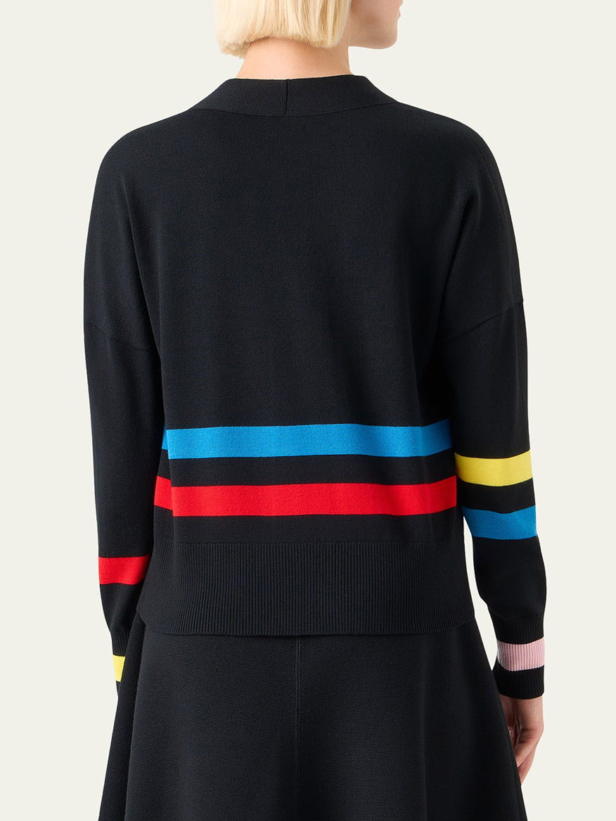 Person with short blonde hair wearing the Akris Punto Striped Merino Knit Cardigan in Black Multi, featuring red, blue, and yellow colorblock stripes, viewed from the back.
