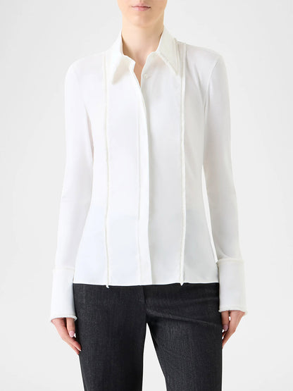 A person wearing an Akris Punto Mixed Media Fringed Button-Down Blouse in Cream with black pants, standing against a plain light background.