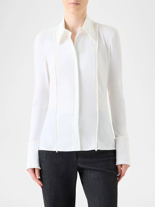 A person wearing an Akris Punto Mixed Media Fringed Button-Down Blouse in Cream with black pants, standing against a plain light background.