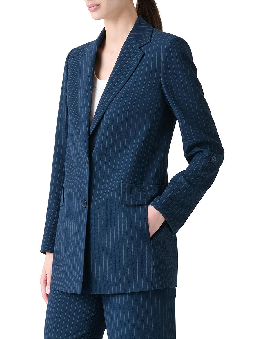 A person wearing the Akris Punto Pinstripe Virgin Wool Jacket in Navy/Cream with matching trousers, left hand in pocket, shown from the waist up.