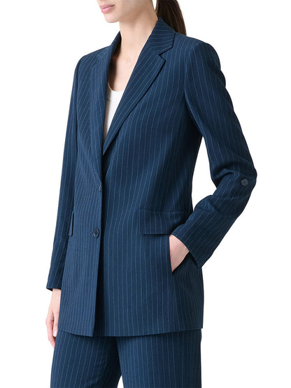 A person wearing the Akris Punto Pinstripe Virgin Wool Jacket in Navy/Cream with matching trousers, left hand in pocket, shown from the waist up.