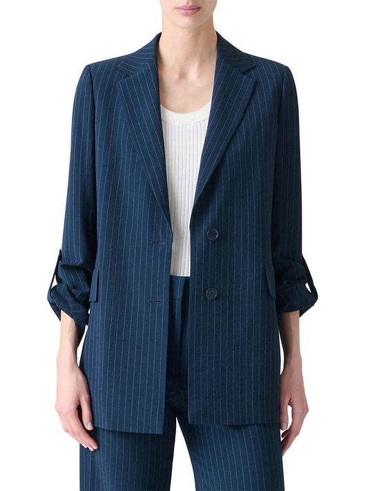 A person wearing an Akris Punto Pinstripe Virgin Wool Jacket in Navy/Cream with matching pinstripe pants and a white ribbed top, standing against a plain background.