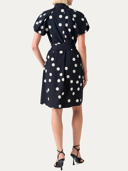 A woman stands with her back to the camera, wearing the Akris Punto Polka Dot Balloon Sleeve Shirtdress in Black/Cream and black high-heeled sandals for an elegant look.