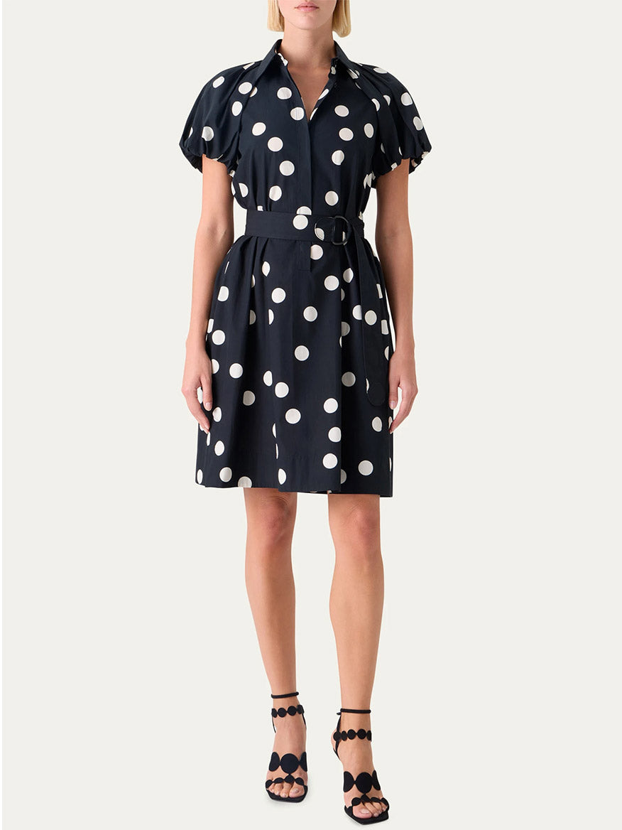 A woman wears the Akris Punto Polka Dot Balloon Sleeve Shirtdress in Black/Cream with black open-toe sandals featuring circular accents.