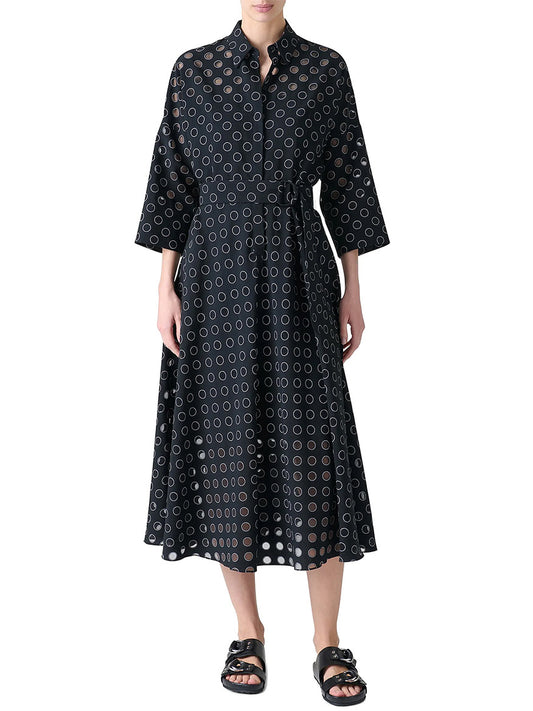 A person wearing the Akris Punto Midi Polka Dot Organzino Belted Dress in Black/Cream with black sandals stands against a white background.