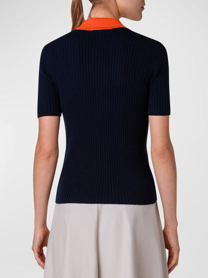 The back view of a woman wearing an Akris Punto Ribbed Wool Polo Top in Navy Multi with orange contrast detailing.