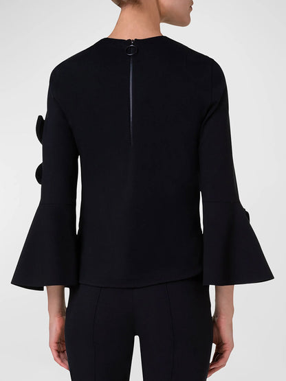The back view of a woman wearing an Akris Punto Cutout Blouse with Bird Applique in Black with bell sleeves from Akris Punto.
