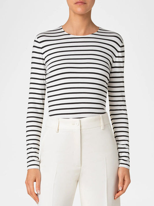 A person wearing the Akris Punto Sailor Stripes Crew in cream/black, made from stretchy jersey, paired with high-waisted white pants, stands against a plain background.