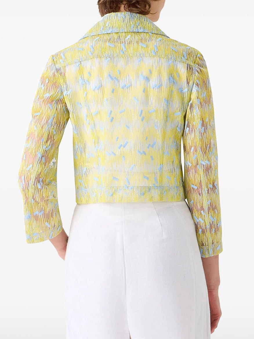 Someone wearing an Akris Punto Scribble Dot Embroidery Biker Jacket in Lemon Zing/Sky Blue, featuring long sleeves, paired with high-waisted white pants and seen from the back.