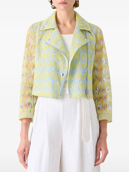 A person wears the Akris Punto Scribble Dot Embroidery Biker Jacket in Lemon Zing/Sky Blue over a white top and white pants, shown from the waist up.