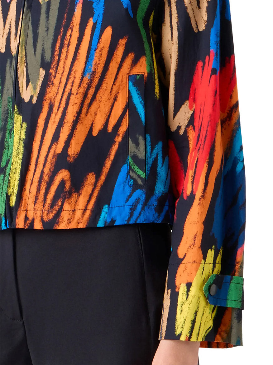 A close-up of a person wearing the Akris Punto Scribble Print Drawstring Jacket in Black Multi and black pants; only part of the torso and arm are shown.