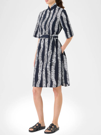 Woman wearing the Akris Punto Scribble Wave Shirt Dress in Black/Cream, a knee-length short-sleeve shirtdress with matching belt and black sandals, standing against a plain light background.