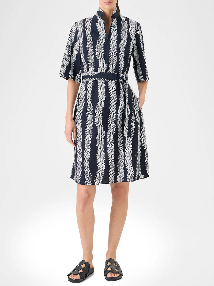 A person wears the Akris Punto Scribble Wave Shirt Dress in Black/Cream, a knee-length, short-sleeve shirtdress with a scribble striped print, paired with black sandals.