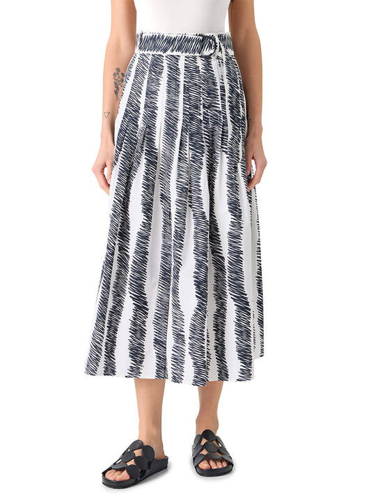 A person wears a white sleeveless top, the Akris Punto Scribble Wave Print Midi Skirt in Cream/Black, and black sandals.