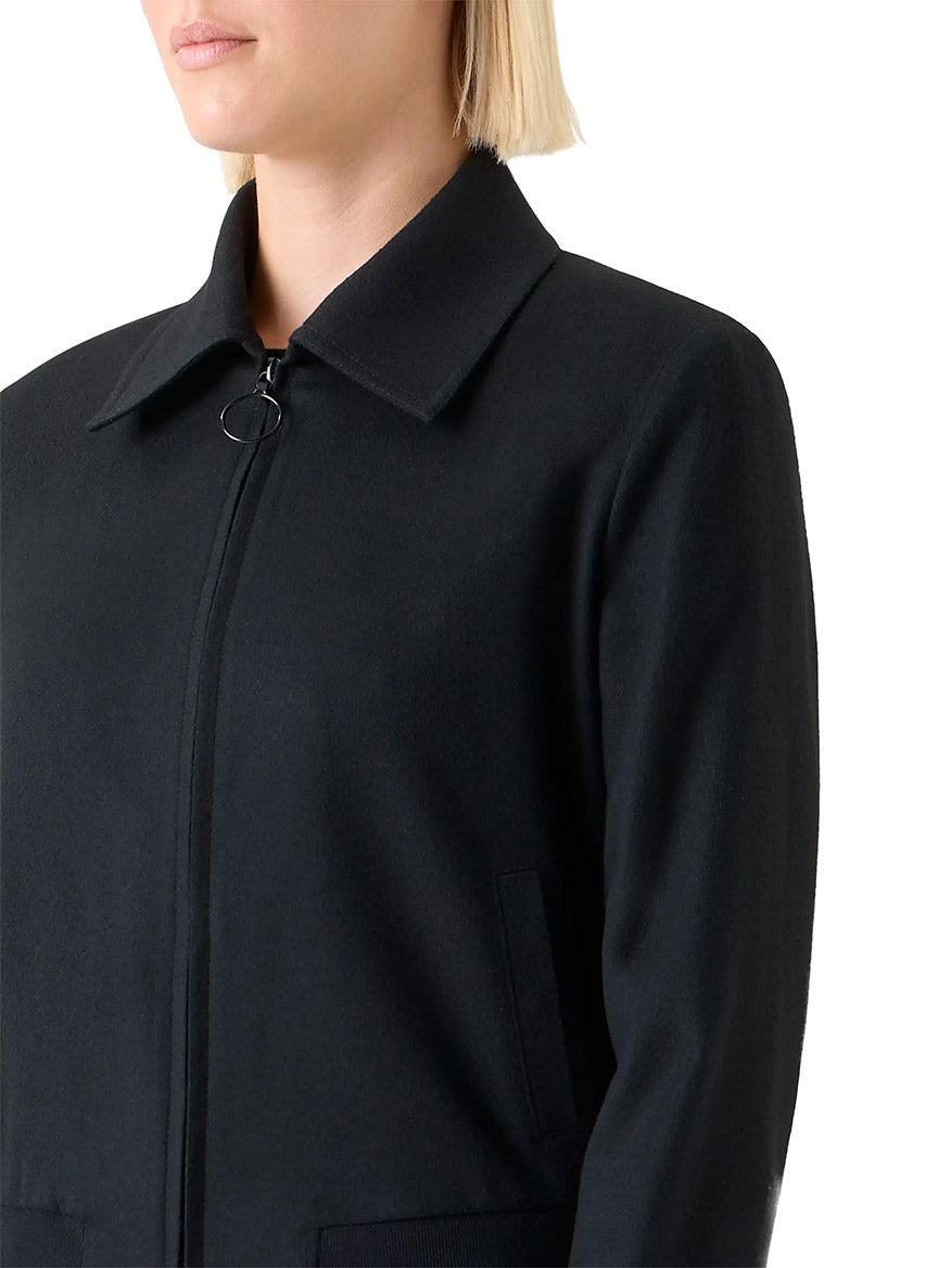 A woman with short blonde hair models the Akris Punto Wool/Cashmere Short Bomber Jacket in Black, featuring rib-knit trim and side pockets, shown from the chest up against a plain white background.