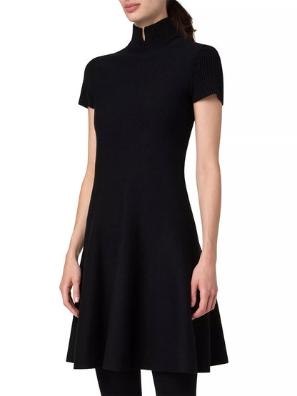 A woman wearing an Akris Punto Short Fit-and-Flare Mockneck Wool Dress in Black, standing against a plain white background.