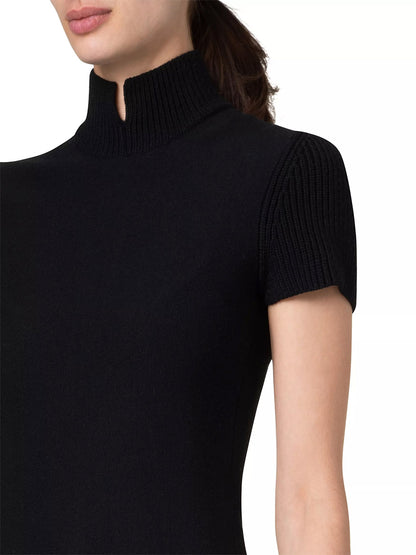 A close-up of a person wearing the Akris Punto Short Fit-and-Flare Mockneck Wool Dress in black against a white background. Only the left shoulder, neck, and part of the face are visible.