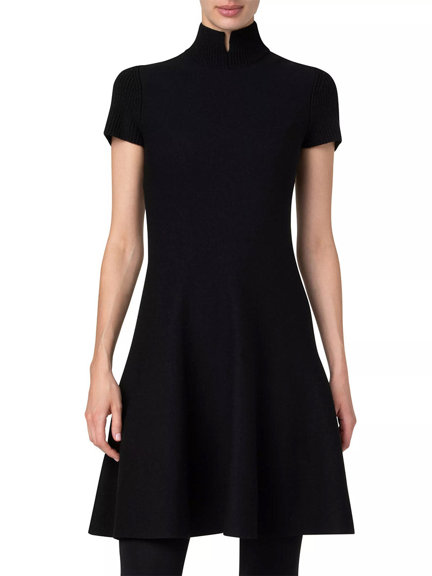 A woman wearing an Akris Punto Short Fit-and-Flare Mockneck Wool Dress in black, standing against a plain white background.