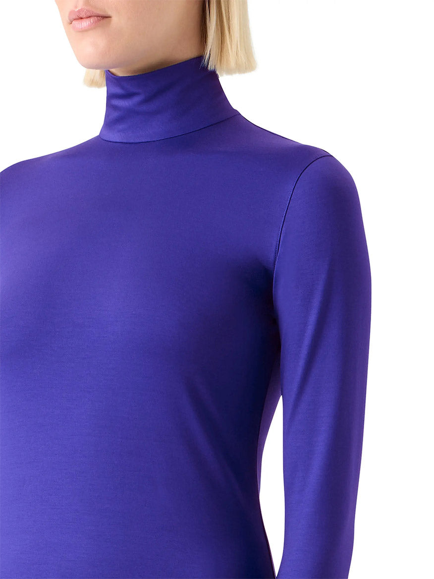 A person with blond hair wears an Akris Punto Mock Neck Signature Dot Jersey Turtleneck in Ultra Violet.