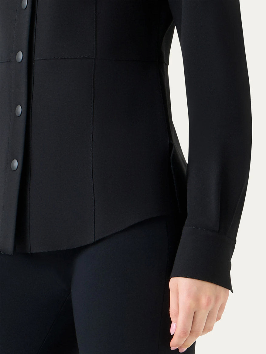 A person wearing the Akris Punto Signature Viscose Jersey Slim Shirt in Black and black pants; only their torso, right arm, and hand are visible.