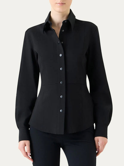 A person wears the Akris Punto Signature Viscose Jersey Slim Shirt in black, featuring a collared, long-sleeve, slim fit design, paired with black pants and standing against a plain light background.