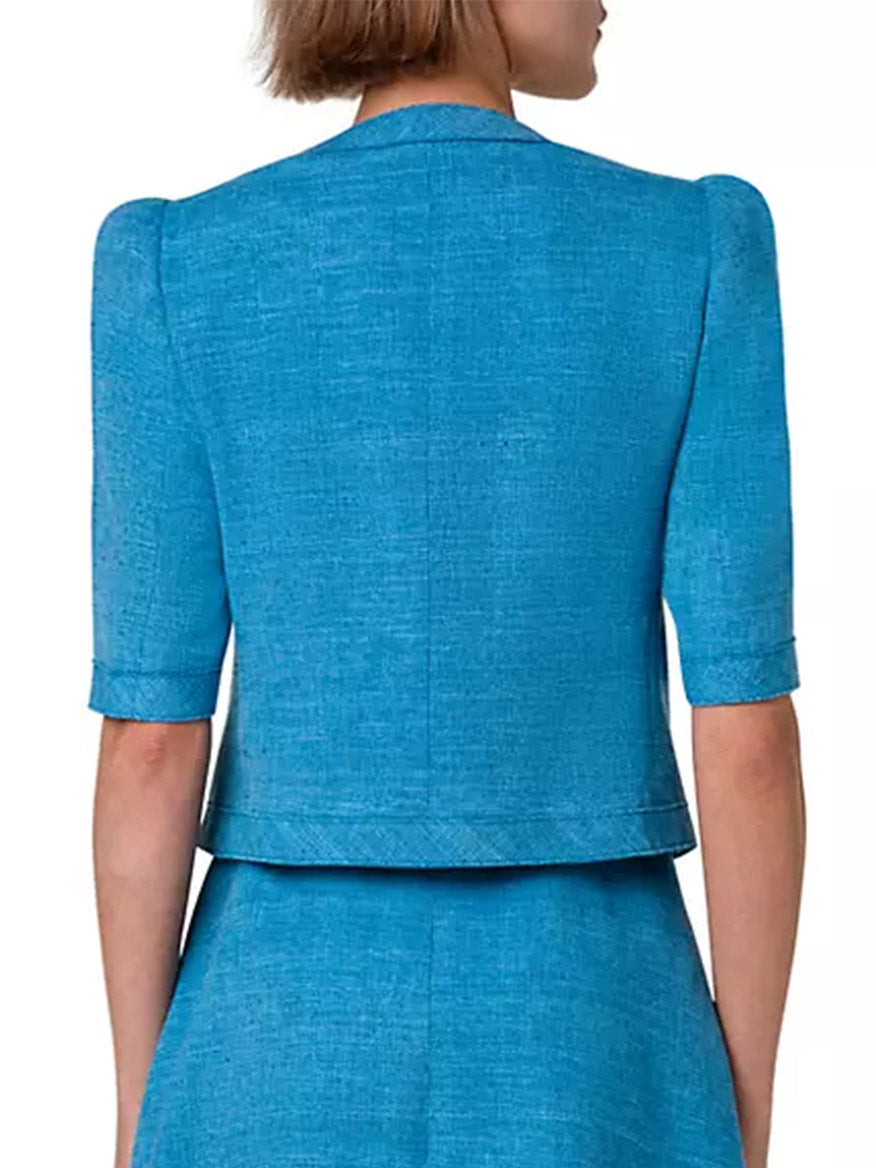 The back view of a woman wearing an Akris Punto Short Sleeve Silk Blend Jacket in Medium Blue.