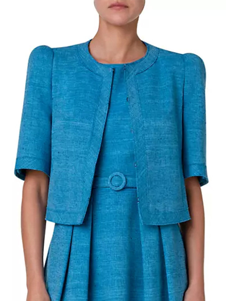 A woman is wearing a blue Akris Punto Short Sleeve Silk Blend Jacket in Medium Blue.