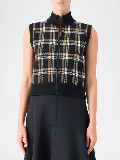 A person models the Akris Punto Sleeveless Plaid Jacquard Zip Sweater in Black/Cream/Camel over a black skirt or dress, shown from shoulders to mid-thigh.