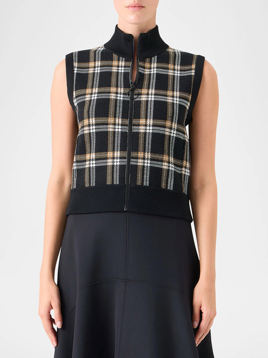 A person models the Akris Punto Sleeveless Plaid Jacquard Zip Sweater in Black/Cream/Camel over a black skirt or dress, shown from shoulders to mid-thigh.