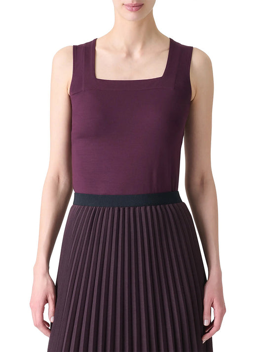 A woman wears the Akris Punto Square-Neck Jersey Tank Top in Blackberry, featuring a sleeveless design and stretch fabric, paired with a matching pleated skirt with a black waistband, standing against a white background.