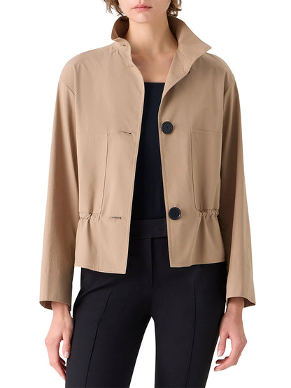 Someone wearing the Akris Punto Stand Collar Parka in Beige, featuring a cotton blend fabric, adjustable drawstring waist, and two front pockets, paired with a black top and black pants.