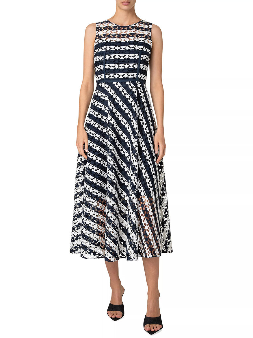 Wearing an Akris Punto Striped Dot Guipure Lace Maxi Dress in Navy/Cream, featuring a sleeveless design with geometric stripes, paired elegantly with black open-toed shoes.